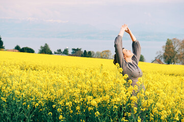Outdoor portrait of happy young woman posing in yellow colza flowers