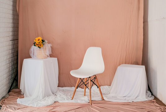 the studio is set up with walls, tables, and the floor is covered with fabric.  setup in the theme of pinkish-orange and white color.