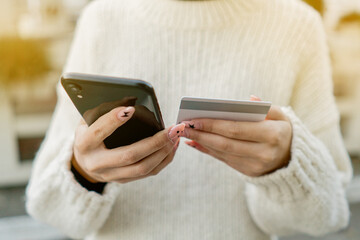 Close-up woman's hands holding a credit card and using smartphone for online shopping