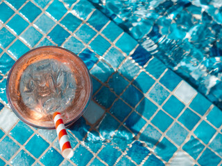 Beautiful glass with a refresh cocktail on the background of the pool. View from above, outdoors,...