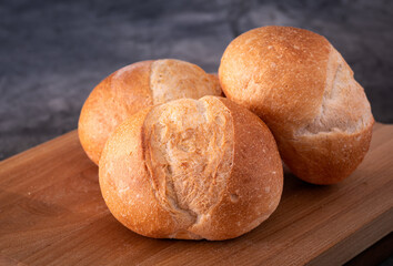 Three Brotchen bread rolls on a wooden cutting board; copy space
