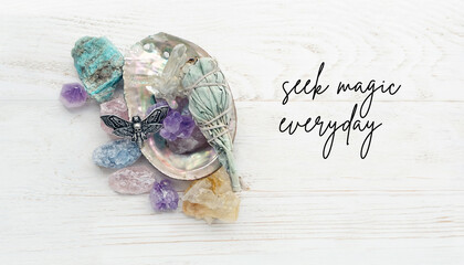 minerals, amulet, sage bundle on sea shell on wooden background. Seek magic everyday. holy sage...