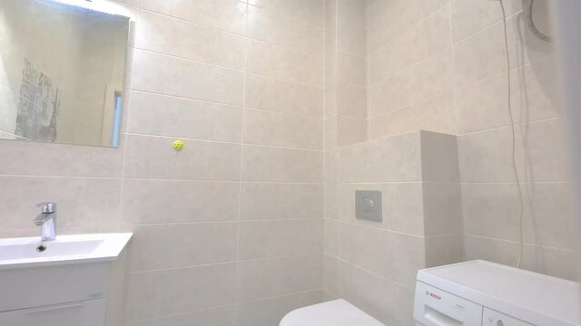 A bright bathroom features white tiles, a floating sink with a mirror, a toilet, and an accent wall with a Parisian scene.