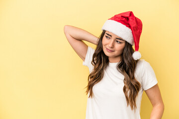 Young caucasian woman celebrating Christmas isolated on yellow background touching back of head, thinking and making a choice.