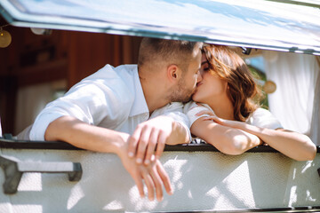 Stylish couple of happy newlyweds posing near trailer. Camping season. Romantic moment. Together. Wedding. Marriage.