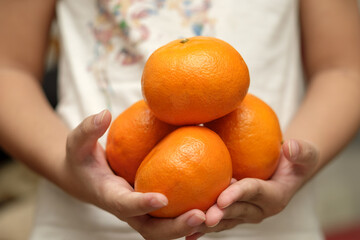 Fresh honey Murcott oranges placed on a man hands, with dressed in white clothes. 