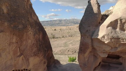 Drone flies backwards between rocks in form of fairy chimneys. Cappadocia, Turkey.