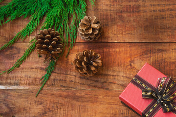 Christmas background. Spruce branches, gift, pinecones on a wooden background. Copy space