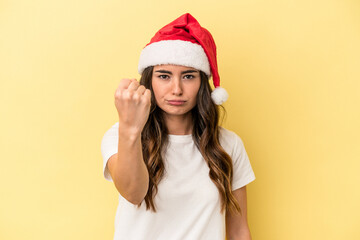 Young caucasian woman celebrating Christmas isolated on yellow background showing fist to camera, aggressive facial expression.