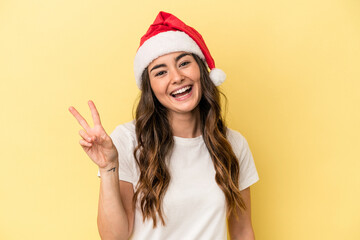 Young caucasian woman celebrating Christmas isolated on yellow background joyful and carefree showing a peace symbol with fingers.