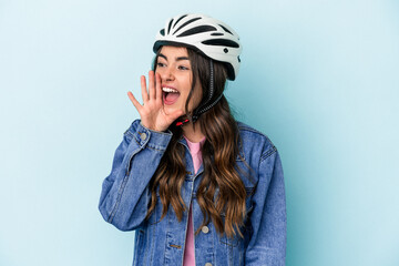 Young caucasian woman rinding a bike isolated on blue background shouting and holding palm near opened mouth.