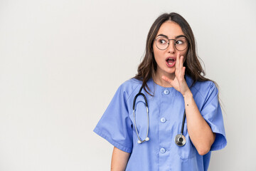 Young caucasian nurse woman isolated on white background is saying a secret hot braking news and looking aside