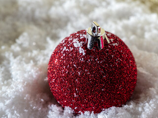Red Christmas ball in the snow on a background of golden glitter.
