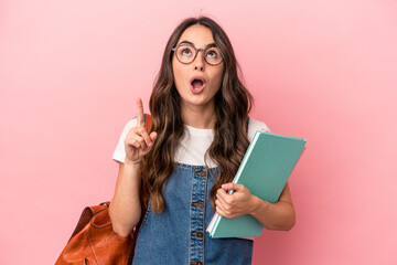 Young caucasian student woman isolated on pink background pointing upside with opened mouth.