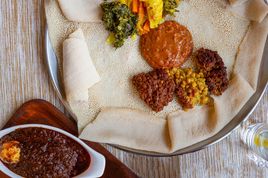 Top down view of traditional vegetarian injera meal, with shiro, lentils, egg and a variety of vegetables