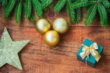 Christmas background. Spruce branches, New Years balls and star, and gift on a wooden background.