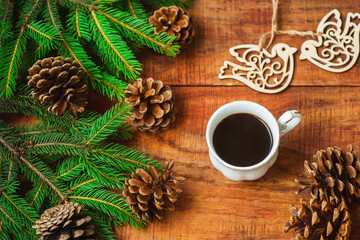 Obraz na płótnie Canvas Christmas background. Spruce branches, wooden bird figures cones and cup with coffee on a wooden background.