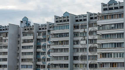 Bottom view of a multi-storey panel residential building on dramatic sky background. City life view.