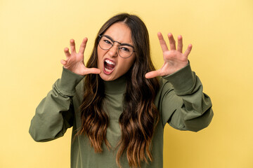 Young caucasian woman isolated on yellow background upset screaming with tense hands.