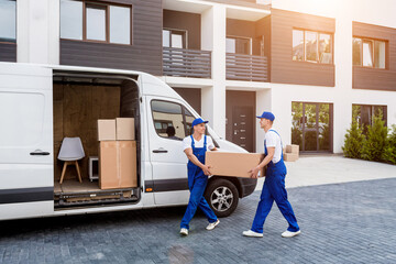 Two removal company workers are loading boxes into a minibus.