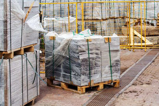 Lots of paving stones in a package on a wooden pallet. Street and sidewalk paving material is stored at the construction site. Selective focus