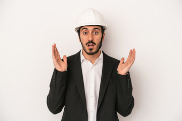 Young architect man wearing a construction helmet isolated on white background surprised and shocked.