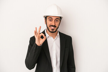 Young architect man wearing a construction helmet isolated on white background cheerful and confident showing ok gesture.