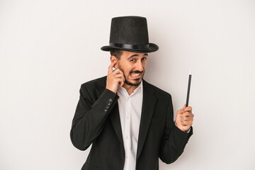 Young magician man holding wand isolated on white background covering ears with hands.