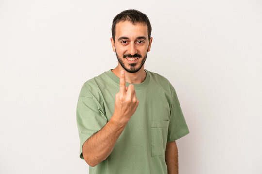Young caucasian man isolated on white background pointing with finger at you as if inviting come closer.