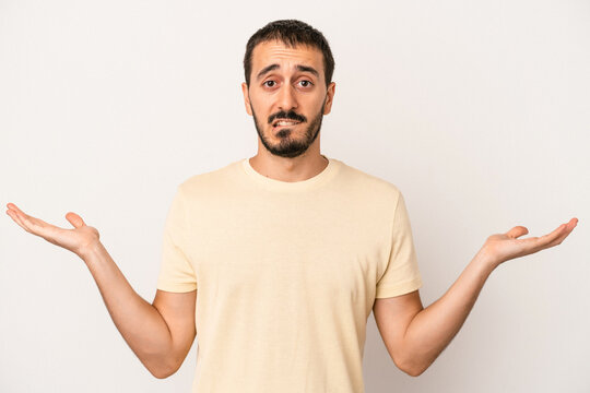Young caucasian man isolated on white background confused and doubtful shrugging shoulders to hold a copy space.