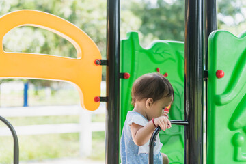 A pretty smiling girl is happily climbing in the playground at Adventure Park.