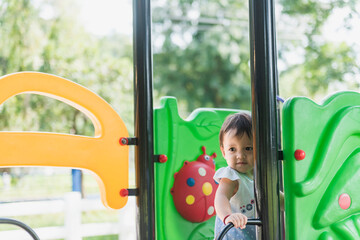 A pretty smiling girl is happily climbing in the playground at Adventure Park.