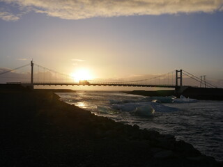 Sunset over a wired bridge with icebergs floating in river in Iceland, with pastel warm sky during winter