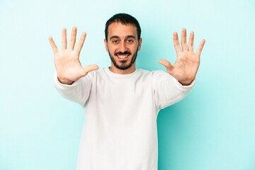 Young caucasian man isolated on blue background showing number ten with hands.