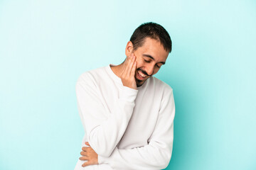 Young caucasian man isolated on blue background laughs happily and has fun keeping hands on stomach.