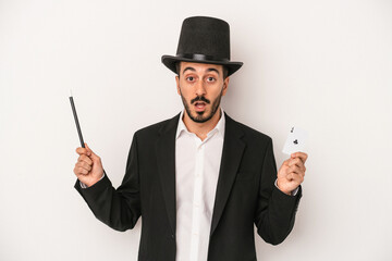 Young magician man holding wand and magic card isolated on white background