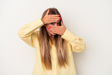 Naklejka premium Young Russian woman isolated on white background blink at the camera through fingers, embarrassed covering face.