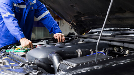 Car mechanic working on car engine, car maintenance concept.