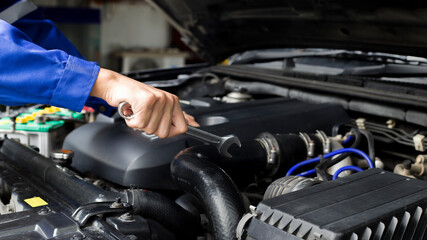 The mechanic works on the engine of the car in the garage, car repair service.