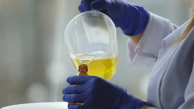 Pour golden healing oil into small bottles in the production of environmentally friendly medical products