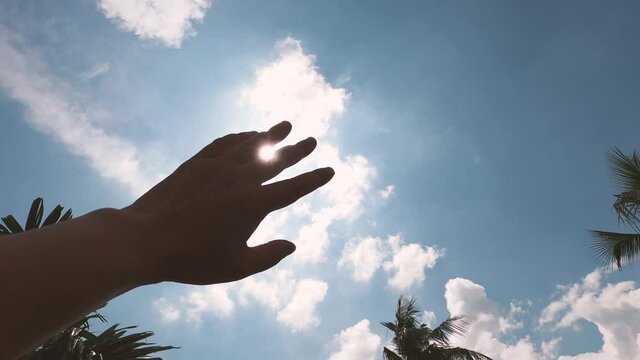 Hot summer sunlight rays pouring through human hand. Hand covering sun light heat temperature. Protection from ultraviolet light and sunburn background. Sunstroke, heatstroke, greenhouse effect.