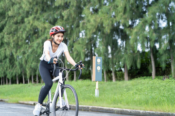 Asian young sport woman riding bicycle in the evening in public park. 