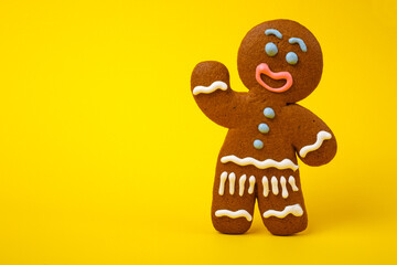 Smiling gingerbread man standing on a yellow background 