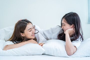 Asian beautiful lesbian couple wake up from sleep in bedroom in morning.