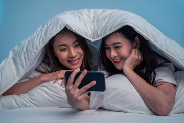 Asian attractive lesbian couple use mobile phone watch movie on bed. 