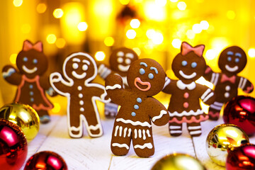 Festive christmas background with gingerbread men. Gingerbread man and woman on a bright golden background with Christmas decorations 
