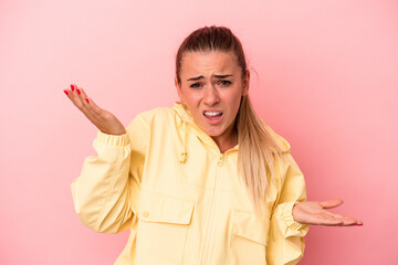Young Russian woman isolated on pink background confused and doubtful shrugging shoulders to hold a...