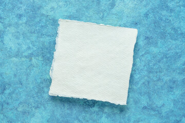 small square sheet of blank white Khadi paper against blue amate bark paper