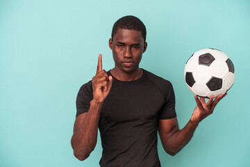 Young African American man playing football isolated on blue background showing number one with finger.