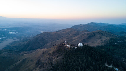 Astronomical observatory located in the highest part of the mountains, during a colorful sunset in...